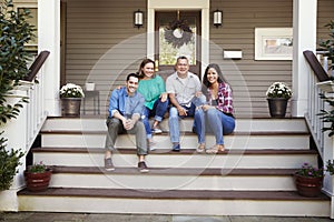 Parents With Adult Offspring Sitting On Steps in Front Of House