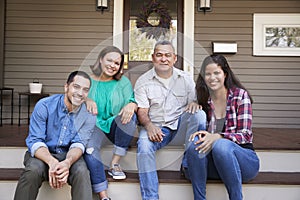 Parents With Adult Offspring Sitting On Steps in Front Of House