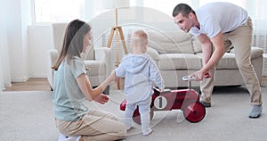 Parents with baby boy having fun using toy car at home