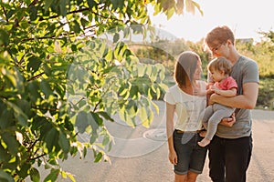 Parents and baby daughter outside in the sunset