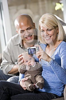 Parents with baby at home, mom holding camera