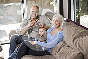 Parents and baby on lap at home, dad with camera