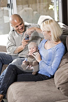 Parents and baby on lap at home, dad with camera photo