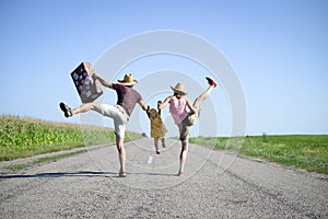 Parents and baby with suitcase jumping and dancing