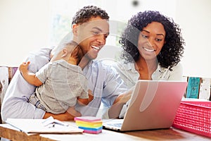 Parents With Baby Working In Office At Home