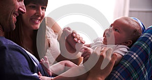 Parents In Bed Playing With Newborn Baby Daughter