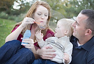 Parents Blowing Bubbles with their Child in Park