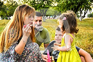 Parents blowing soap bubbles to child. Family love first. Family activity leisure outdoor in autumn park. Mother, father and two