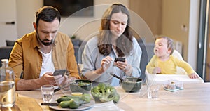 Parents busy in their phones during a lunch with their baby son