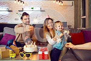 Parents with a cake congratulate their child on his birthday.