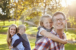 Parents carry their kids piggyback in a park selective focus