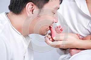 Parents carrying baby. portrait of young family with little son. Mom holding small baby feet. Woman hands holding newborn baby