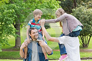 Parents carrying kids on shoulders at park