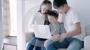 Parents with child watching funny videos using laptop browsing online tv streaming enjoying spending time together