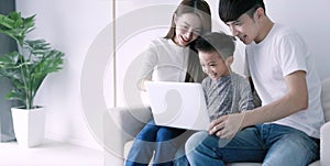 Parents with child watching funny videos using laptop browsing online tv streaming enjoying spending time together