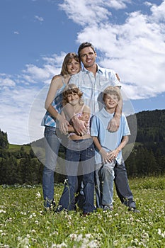 Parents with children (7-9) embracing in field portrait