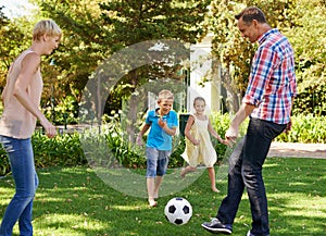 Parents, children and ball in park as family, playing and bonding together with sport. Kids, son and daughter with