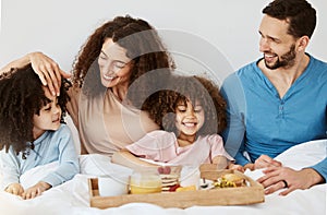 Parents, children and breakfast in bed, morning or excited for love, bonding or care on holiday. Mother, father and kids