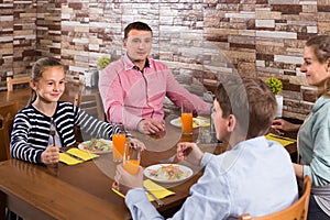 Parents and children chatting during dinner in family cafe