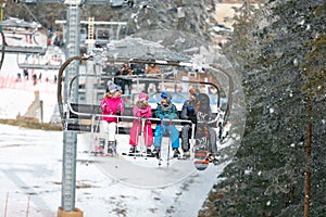 Parents with children climb up on the ski terrain with chair lift