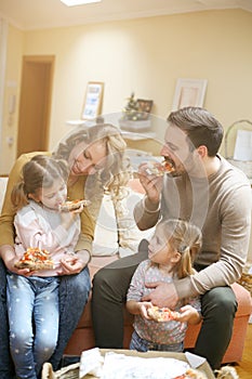 Parents and children eating pizza together. Happy family enjoying in meal together at home.