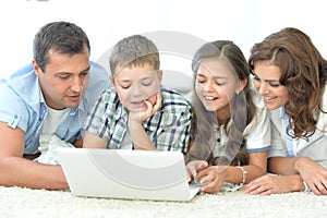 parents with children with laptops are lying on the back