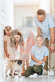 parents and children palming adopted pug dog at animals
