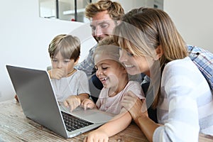 Parents with children playing on laptop