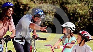 Parents and children pointing the way to go while they are riding bicycle