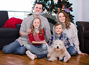 Parents and children posing for photo by Christmas tree