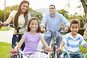 Parents With Children Riding Bikes In Park