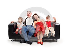 Parents with children sit on black leather sofa