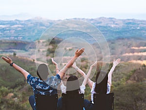 Parents and children sit on lawn chairs at the top of the mountain on vacation. A happy family talks on the top of the mountain