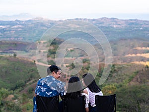 Parents and children sit on lawn chairs on vacation.Happy family use smartphone and talks on the top of the mountain