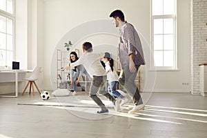 Parents and children spending leisure time together play football at home