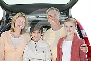 Parents And Children Standing In Front Of Open Car Trunk