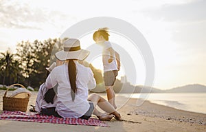 Parents and children who enjoy a picnic at the beach on sunset in holiday.