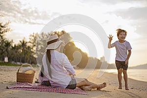 Parents and children who enjoy a picnic at the beach on sunset in holiday.