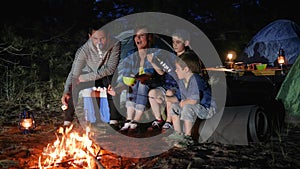 Parents with childs broil marshmallow on campfire to woodland, happy family fry marshmallow at fire