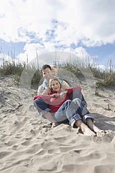 Parents and daughter (5-6) embracing on beach portrait