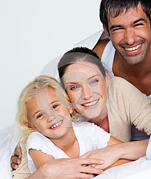 Parents and daughter on bed smiling at the camera