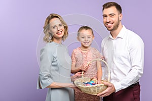 Parents and daughter with Easter basket with colored eggs