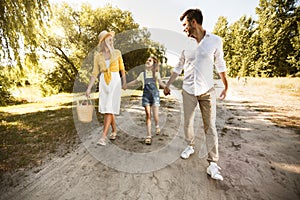 Parents And Daughter Going On Summer Picnic Near River