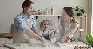 Parents and daughter having fun while cooking in kitchen