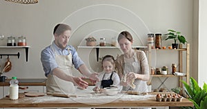 Parents and daughter having fun throwing dough while cooking pastry