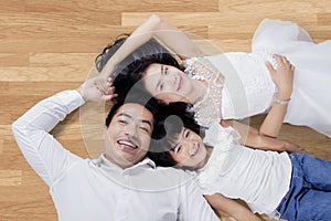Parents and daughter lying on wooden floor