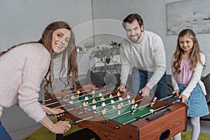 parents and daughter playing table soccer