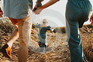 Parents and daughter relationship. Mom and dad hugs their kid. walking on a beautiful fiels.