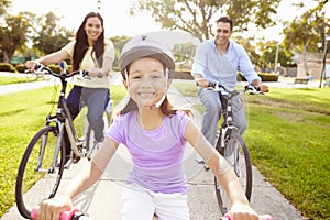 Parents With Daughter Riding Bikes In Park