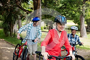 Parents and daughter walking with bicycle in park